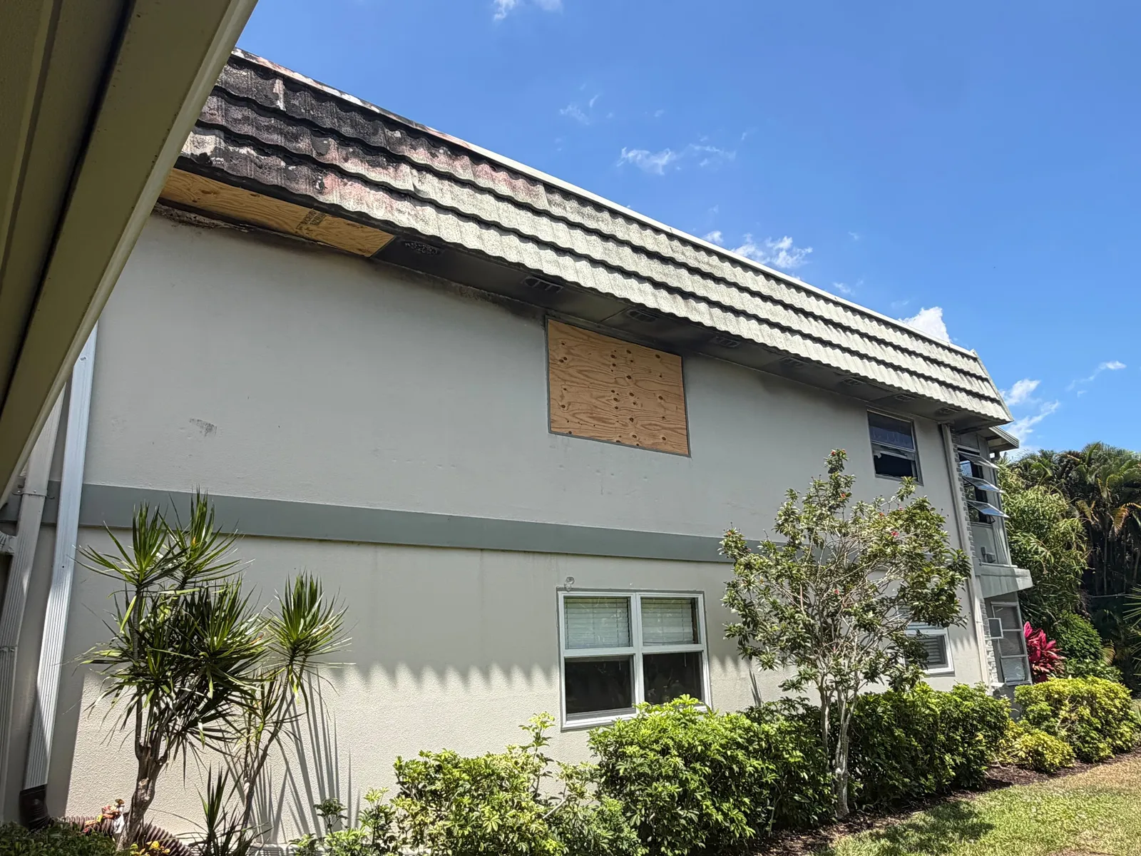Damaged tile roof with boarded window below