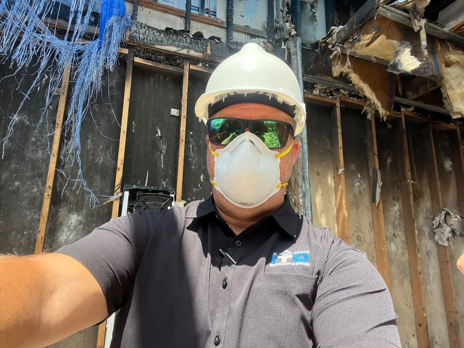 ITD Restoration technician in full PPE at a fire-damaged job site